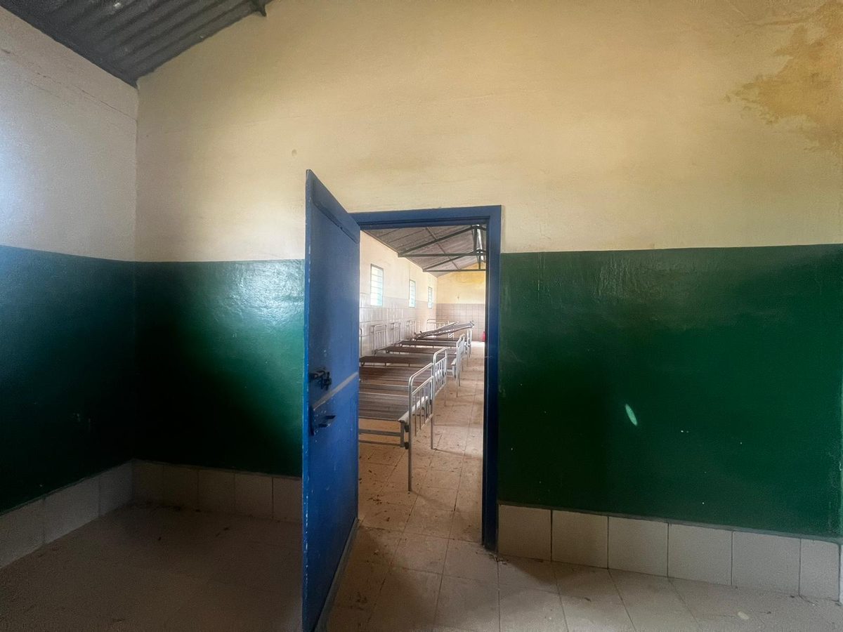 Una stanza vuota con le pareti gialle e verdi e una porta azzurra aperta su un corridoio