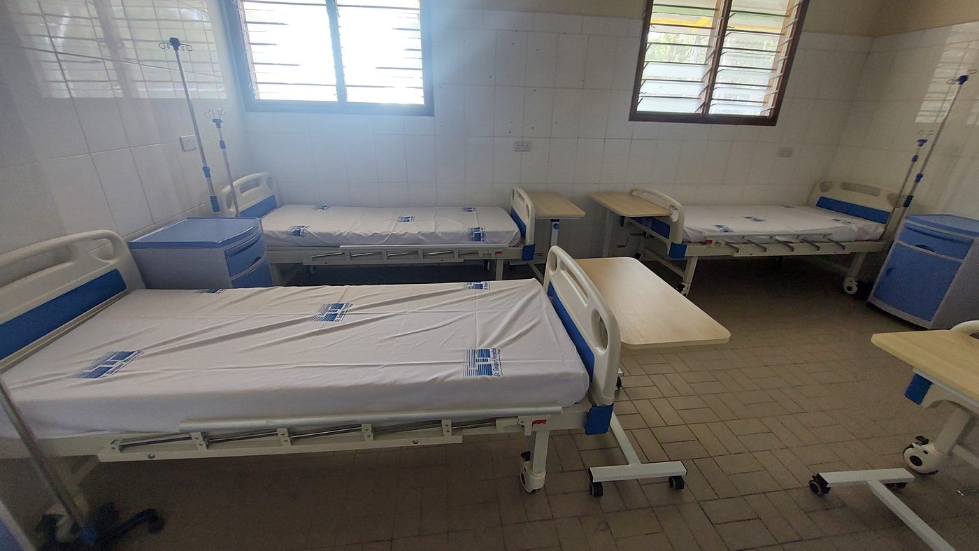 Letti nuovi con i materassi bianchi e i comodini azzurri in una stanza del reparto